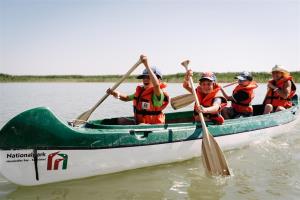 3 students and a ranger are paddeling in lake neusiedl