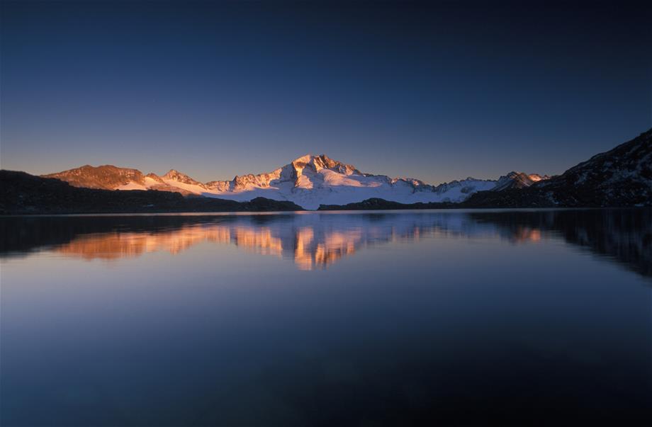A mountain lake with mountains in the background which are in the setting sun