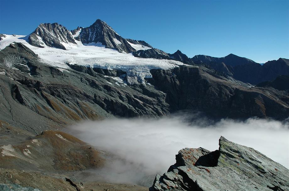 A foggy valley with the glaciated Großglockner in the background