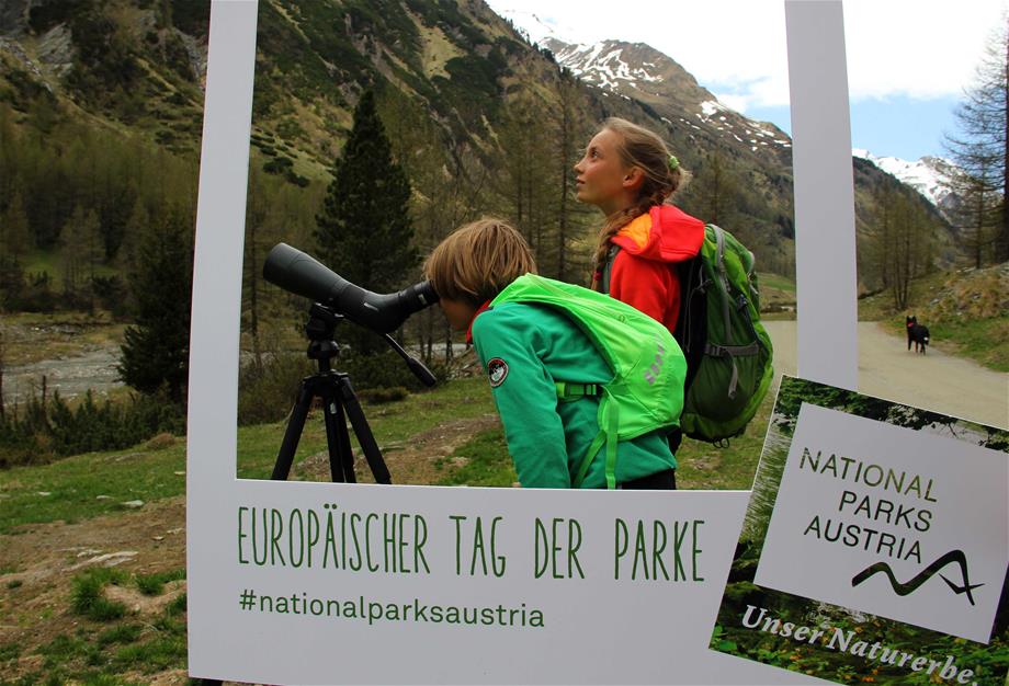 zwei Kinder beobachten mit einem Fernrohr Wildtiere im Nationalpark Hohe Tauern