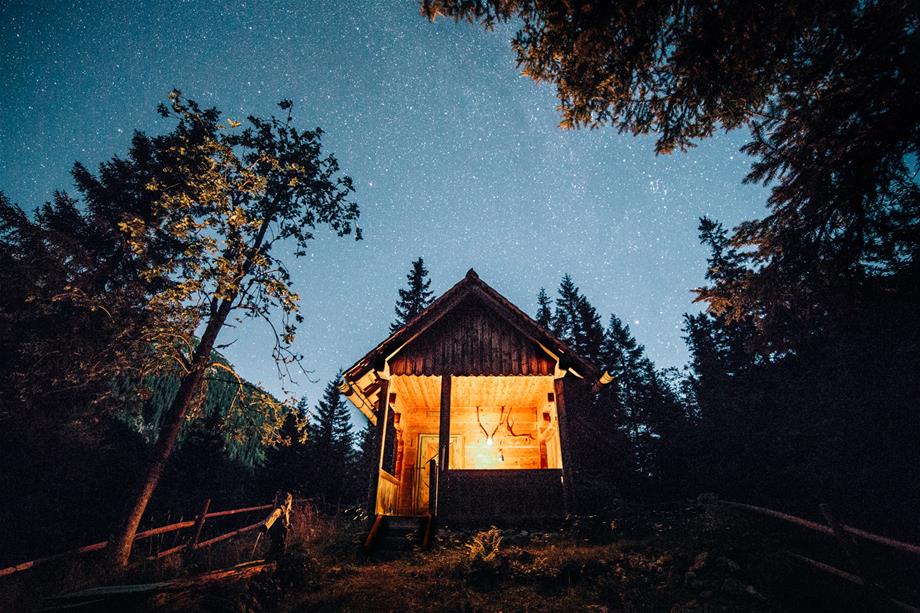 das Bild zeigt eine beleuchtete Hütte am Abend im Nationalpark Gesäuse