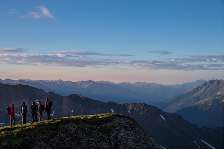 5 hikers are standing on a mountain peak